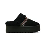 Zueco de plataforma con exterior de gamuza negra y forro de corderito sintético. Presenta un detalle de bordado decorativo en zigzag en tonos naranja y blanco sobre el empeine.