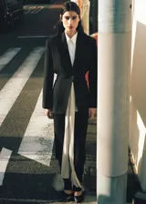 Blazer entallado de color negro, confeccionado en mezcla de lyocell y viscosa, con diseño de cuello en pico con solapas de muesca, manga larga con puños abotonados, cintura fruncida y bolsillos de parche laterales.
