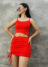 Vestido corto rojo ajustado, con breteles finos y detalle de frunce lateral con lazos.