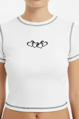 Remera crop negra de manga corta, con costuras visibles en contraste, cuello redondo y un estampado en el pecho con diseño de candado en forma de corazón.