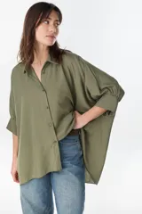 Camisa de manga larga color verde militar, con cuello camisero, cierre frontal con botones y diseño amplio.