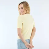 Sweater de punto color amarillo pastel, con cuello en V, manga corta y cierre frontal con botones decorativos en forma de estrella de mar.