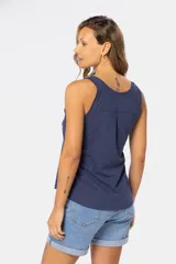 Musculosa blanca sin mangas, de corte clásico y calce cómodo, confeccionada en tejido suave. Presenta escote redondo, cartera con botones frontales y un pequeño bolsillo aplicado en el pecho.