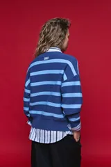 Cardigan tejido a rayas horizontales en tonos azul y celeste, con cuello redondo, hombros caídos y cierre frontal con botones.
