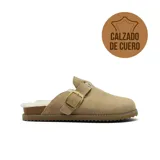 Zueco de cuero gamuzado color tostado, con interior forrado en piel sintética, hebilla metálica ajustable en el empeine y suela de goma con textura dentada.