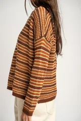 Sweater de punto con diseño de rayas horizontales en tonos ocre, marrón y crudo. Presenta cuello redondo, mangas largas y puños acanalados.