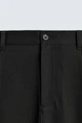 Pantalón de corte recto confeccionado en tejido elástico, con cintura elástica, pliegues frontales, bolsillos laterales y bolsillos traseros de vivo con botón.