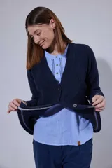 Saco tejido en lambswool con diseño de rombos y trenzas en el frente. Presenta cierre frontal con botones, cuello en V y detalles de rayas en contratono en puños y ruedo. Incluye pin bordado en la manga.