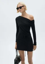 Vestido corto negro de diseño asimétrico con escote de un solo hombro y manga larga. Presenta un corte entallado con detalle de lazo ajustable en la cintura y cierre de cremallera lateral.