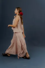 Pollera larga de lino color gris topo, de diseño amplio con volumen, movimiento y bolsillos delanteros. Cuenta con elástico en la cintura y detalles de pinzas y sobretelas en los laterales.