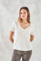 Remera básica de algodón peinado color marfil, de manga corta y cuello en V, con detalle de pequeño bordado rojo en el escote.