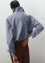 Camisa de corte recto con diseño de rayas, cuello camisero, manga larga con puños abotonados, bolsillo de parche en el pecho y cierre delantero con botones.