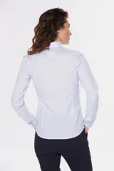 Camisa de tejido Oxford lisa y color blanco, con cuello camisero, cierre frontal de botones y mangas largas con puños abotonados.