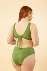 Trikini verde con estampado de hojas, escote redondo, corte en los laterales unidos por un aro metálico y nudo en la espalda.