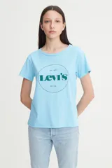 Remera de algodón color celeste con cuello redondo y mangas cortas. Presenta un estampado gráfico circular en el frente con el logo de la marca en color verde oscuro.