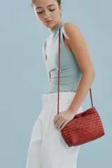 Cartera tipo morral y bandolera de cuero vacuno marrón, completamente trenzada a mano con diseño estructurado y correa larga trenzada.