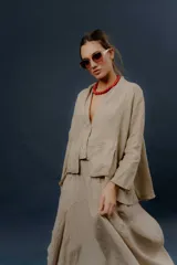 Chaqueta de lino color beige, de calce relajado, con escote en V, cierre frontal con botones y bolsillos frontales aplicados.
