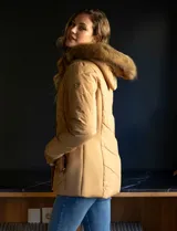 Campera de abrigo negra marca Michael Kors, con cierre central oculto y botones a presión, bolsillos delanteros, puños elastizados, avíos metálicos dorados con logo y capucha de piel sintética desmontable.