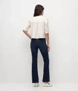 Blusa cropped de satén color crema, con cuello redondo, mangas cortas abullonadas con hombreras y detalle de fruncido en el frente.