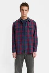 Camisa de manga larga con diseño a cuadros en tonos bordó, azul y verde. Presenta cuello clásico, cierre frontal con botones y dos bolsillos en el pecho con solapa. Confeccionada en tejido de algodón.