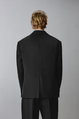 Blazer regular fit de lana color negro, con solapas de muesca, cierre frontal de un botón, bolsillos con solapa en la cadera y manga larga.
