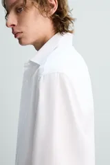 Camisa de corte slim fit con textura, cuello italiano y manga larga con puños abotonados. Presenta cierre frontal con botones.