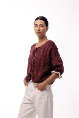 Saco de punto gris con frente abierto y cierre mediante lazos frontales. Presenta mangas abullonadas con puños elásticos y un diseño de textura voluminosa.