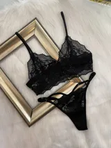Conjunto de lencería compuesto por un top bralette de encaje con breteles regulables y una tanga colaless regulable con detalles de tiras.