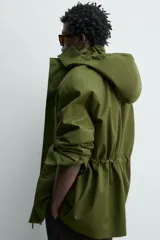Parka técnica color verde militar de corte relaxed fit con cuello subido y capucha desmontable. Cuenta con bolsillos con solapa en el pecho y en la cadera, cintura ajustable con cordón y cierre frontal de cremallera oculta por solapa con botones a presión. Incluye un chaleco interior desmontable acolchado.