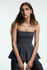 Top strapless de punto con escote recto y diseño ajustado en el torso que se abre en un peplum acampanado en la cintura.