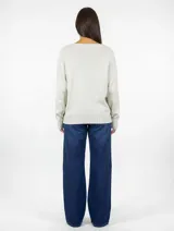 Buzo de punto color beige con cuello redondo y diseño de tejido liso. Presenta mangas largas con puños acanalados y ruedo también acanalado, ofreciendo un corte recto y holgado.