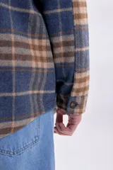Sobrecamisa a cuadros en tonos azul marino, beige y marrón, con cierre frontal de botones, bolsillos con solapa en el pecho y mangas largas.