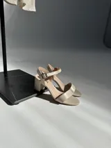 Sandalias de taco cuadrado y altura media, con tira delantera y tira ajustable al tobillo con hebilla metálica.