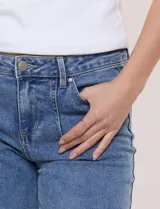 Pantalón jean denim de tiro medio y calce holgado, con pierna de corte recto y lavado con sutil desgaste en costuras. Cuenta con bolsillos funcionales frontales, recortes verticales y cierre frontal con cremallera y botón metálico.