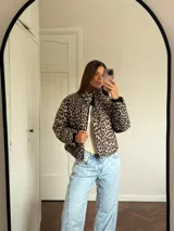 Campera puffer con estampado de leopardo en tonos blanco y negro, cuello alto, cierre frontal y bolsillos laterales.
