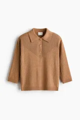 Top corto color tostado en tejido de punto acanalado fino, con cuello tipo polo, tapeta de tres botones y manga tres cuartos. Cuenta con remate acanalado en puños y bajo.