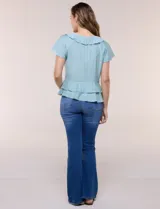 Blusa de satén texturizado color verde menta, con escote en V y volados que bordean el cuello. Presenta mangas cortas acampanadas y doble nivel de volados en la parte inferior, formando una silueta péplum.