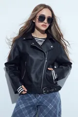 Campera biker de cuero sintético en color negro, con cierre frontal diagonal, bolsillos laterales con cierre y cinturón ajustable en la cintura con hebilla metálica.