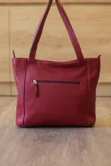 Cartera tipo tote de cuero vacuno negro con doble asa de hombro, panel superior liso y bolsillo exterior frontal con textura símil cocodrilo y costuras visibles en contraste.