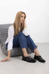 Mocasines de charol color bordó, de diseño vanguardista con corte asimétrico en el empeine, abertura en V, punta fina y suela plana con pequeño tacón.