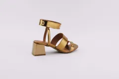 Sandalias negras de cuero con dos tiras horizontales sobre el pie y pulsera al tobillo con ojalillos y tachas. Taco cuadrado de 5 cm.