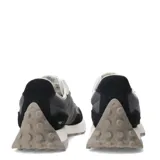 Championes New Balance modelo 327, con capellada en tonos negro, gris oscuro y gris claro. Presenta el logo 'N' sobredimensionado en gris claro y suela de goma blanca con relieve.