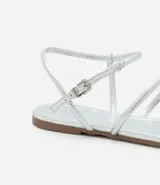 Sandalia plana dorada con tiras finas y cierre con hebilla en el tobillo.