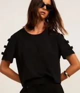 Blusa de crepé negro de manga corta y cuello redondo, con detalles de pequeños lazos aplicados a lo largo de las mangas.