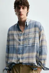 Camisa de corte relajado confeccionada en tejido ligero de algodón, con diseño de cuadros en tonos azules y beige. Presenta cuello solapa, cierre frontal de botones, manga larga con puño abotonado y un bolsillo en el pecho.