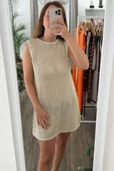 Vestido tejido de punto calado, color beige claro, sin mangas y con cuello redondo.