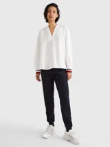 Blusa de manga larga Tommy Hilfiger confeccionada en algodón orgánico. Presenta un cuello en V amplio y puños elásticos con el diseño de rayas distintivo de la marca en colores blanco, rojo y azul marino.