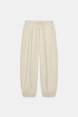 Pantalón de tiro medio y cintura elástica con cordón de ajuste, bolsillos laterales y bajo abullonado con puños elásticos. Confeccionado en poliamida.