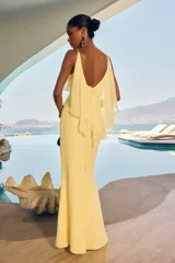 Vestido largo color amarillo de corte sirena, con escote en V, tirantes finos y detalle de volados en el pecho.