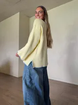 Sweater de punto jersey de algodón color amarillo con silueta oversize, mangas acampanadas y cuello a la base. Presenta terminaciones hechas a mano en crochet a contratono en color celeste con detalles de lurex.